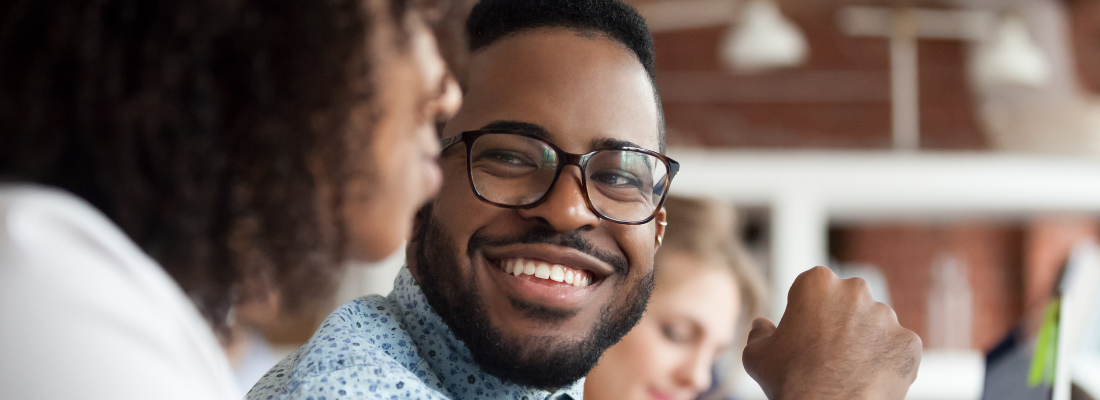 Man listening to and smiling at his female coworker