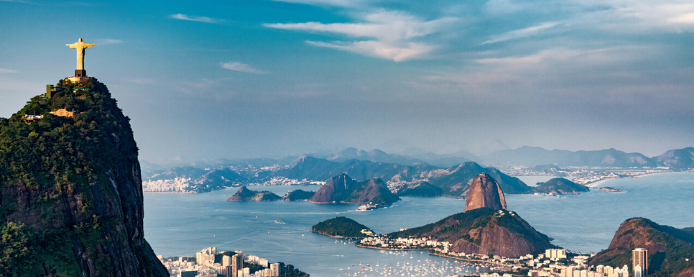 Panoramic view of the Christ the Redeemer statue overlooking Rio de Janeiro's mountains and coastline.