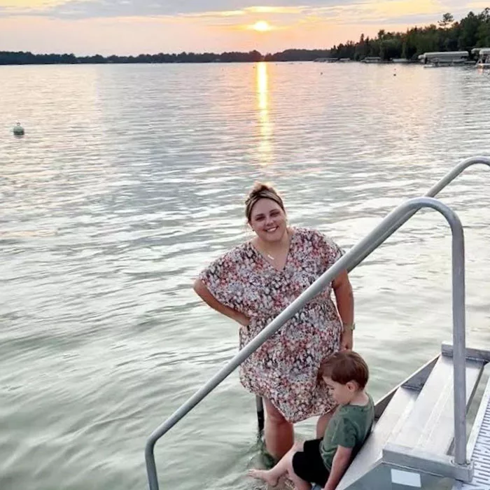 Aperian co-President Amanda Worsfold standing on stairs that lead to the water with her son at sunset
