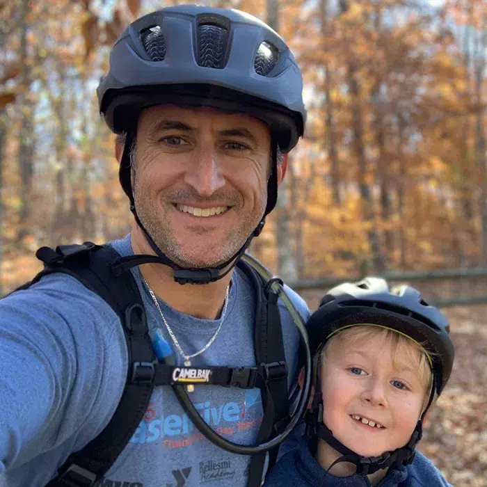 Mike Greto, Aperian co-president, biking with his young son, both wearing helmets