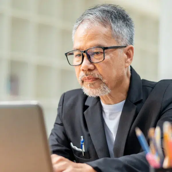 Asian man with glasses looking at computer