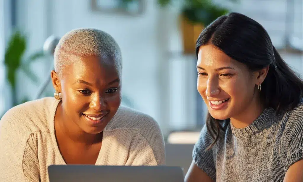 Two women looking at a laptop smiling