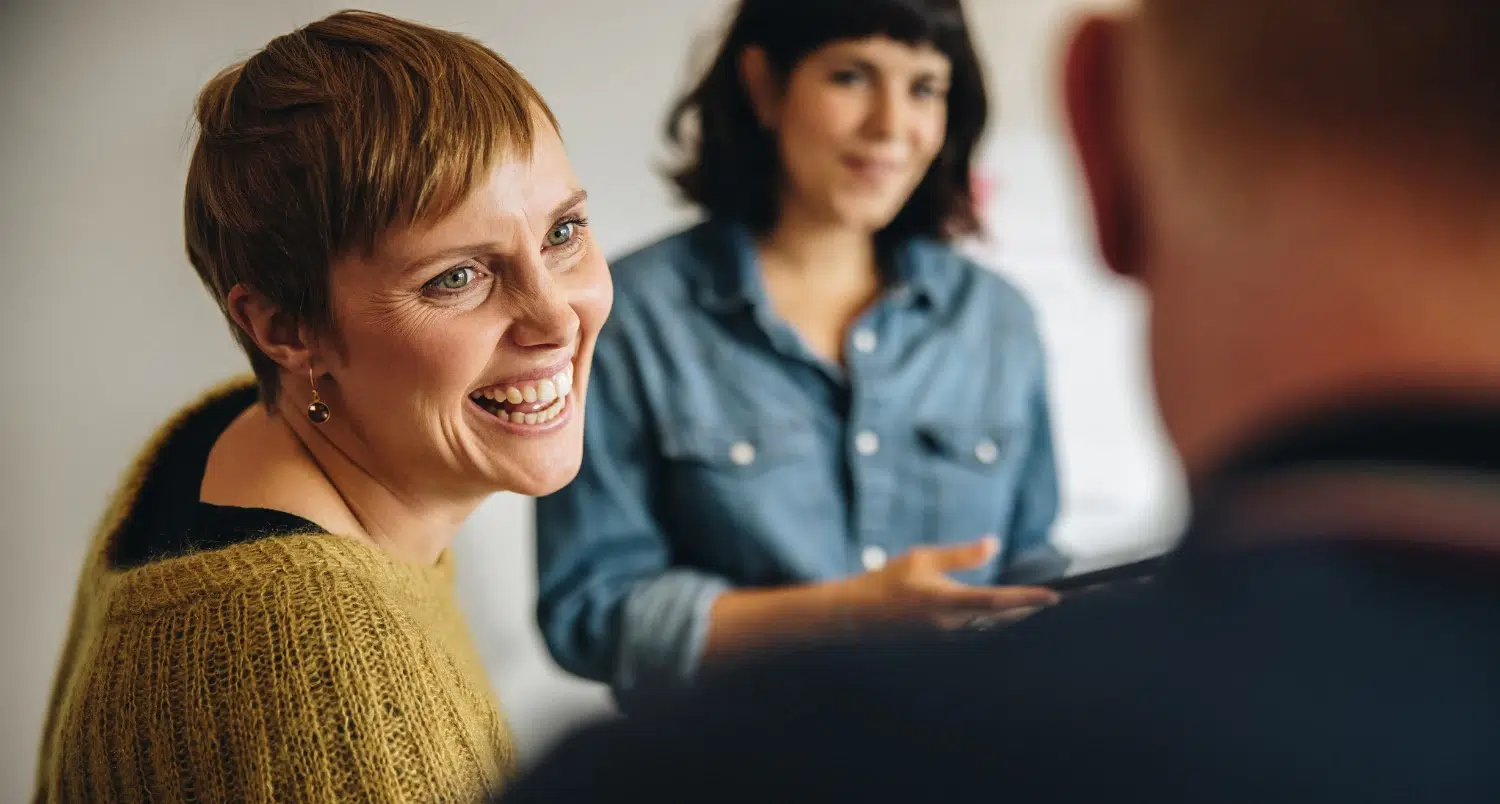 Woman laughing - colleagues in the foreground and background - stock photo