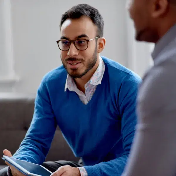 Image of man in glasses sitting and talking with colleagues