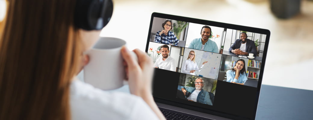 Woman drinking coffee watching a web conference with other colleagues - stock