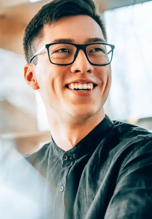 Man wearing glasses smiling while looking over his shoulder