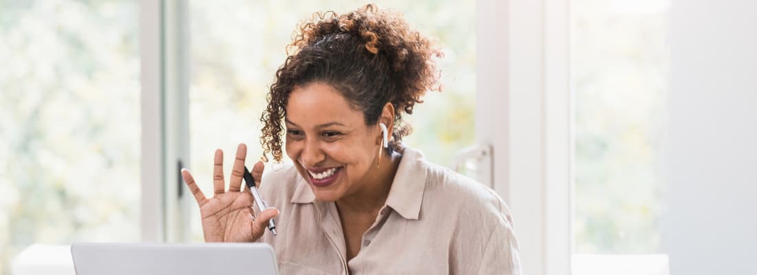 Woman smiling waving at her laptop