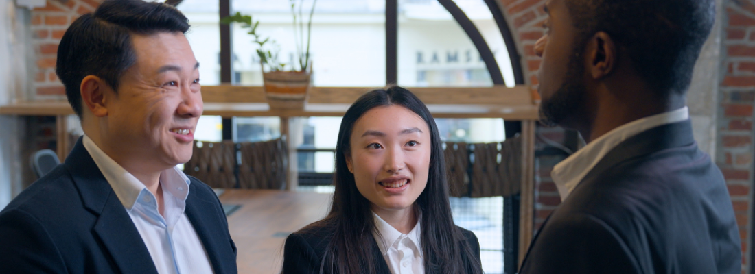 two Japanese professionals speak to a Black professional in a business setting