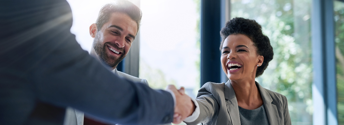 professionals smiling and shaking hands in a business setting