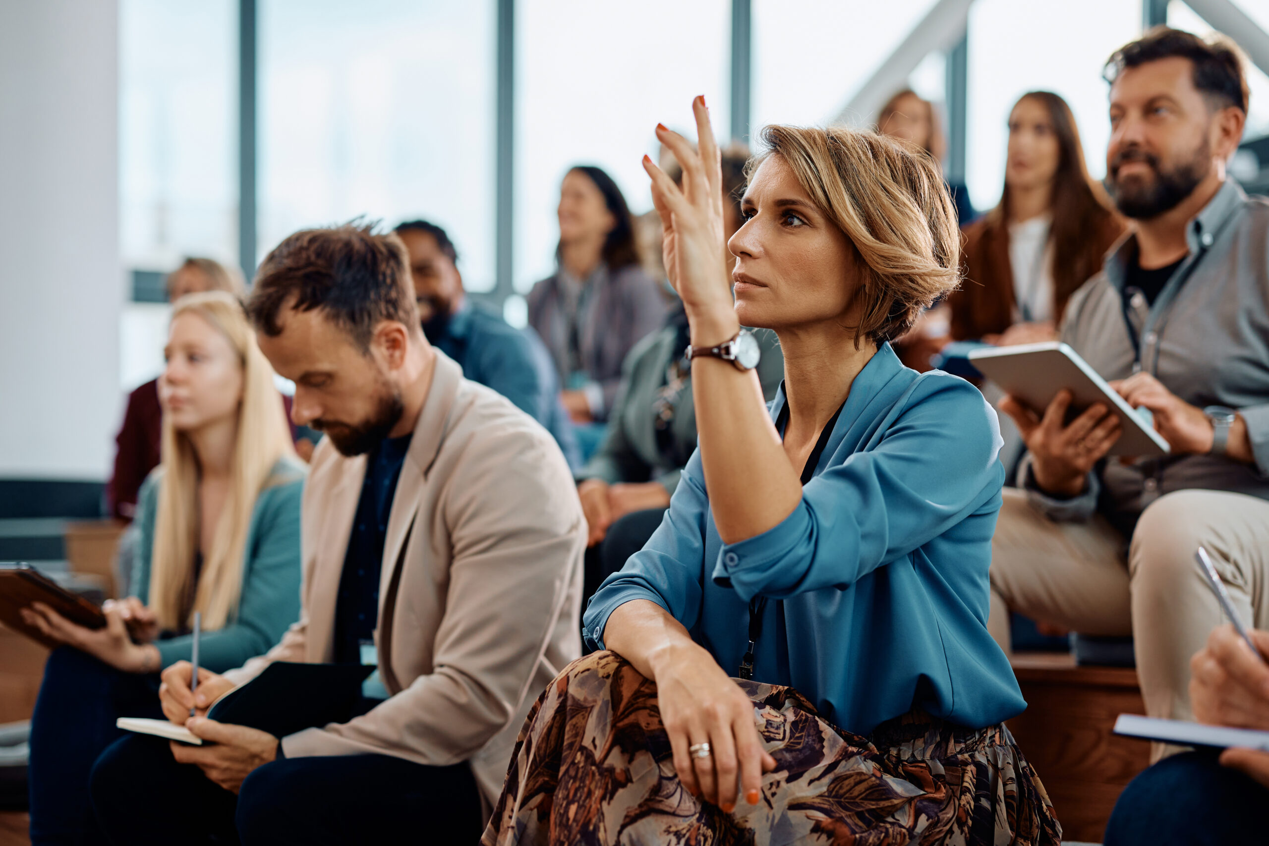 conference room with audience, woman raising hand