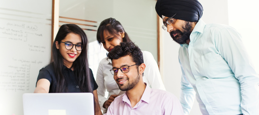 Indian colleagues gathered around a computer for a business meeting